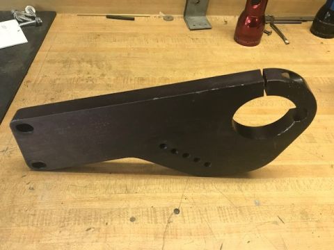 2000 Ford Explorer - A black metal bracket with a circular opening and several mounting holes is shown on a wooden surface.