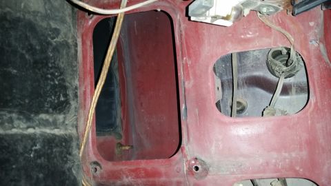 1985 Ford Bronco - Close-up view of the red interior paneling, showing exposed wiring and openings.