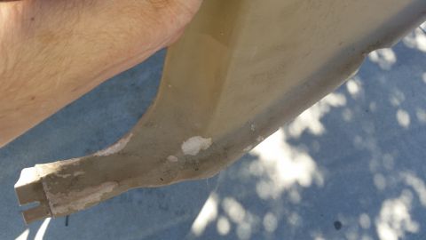 1985 Ford Bronco - Tan plastic interior trim piece showing damage and repair attempts.