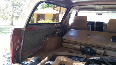1985 Ford Bronco - The interior of a 1985 Ford Bronco, tan seats and a view of the cargo area, appears to be undergoing restoration.