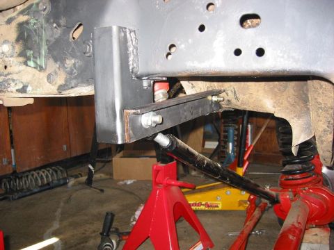 1985 Ford Bronco - Vehicle frame modification in progress, supported by jack stands and a floor jack.