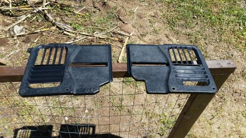 1985 Ford Bronco - Two black interior vent panels are laid out on a wire fence outdoors.