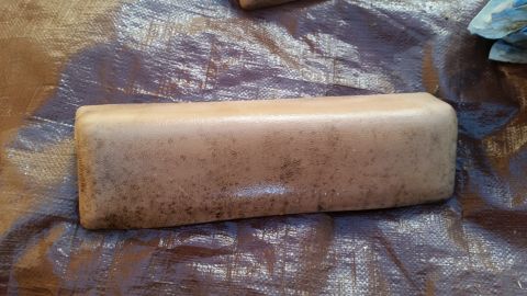 1985 Ford Bronco - A tan armrest, possibly for an older vehicle, rests on a textured brown tarp. The Supermotors.net logo is visible in the lower right corner.