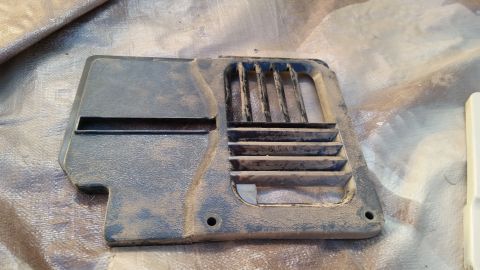 1985 Ford Bronco - A dusty, dark gray plastic trim piece with vent openings is shown against a textured background.