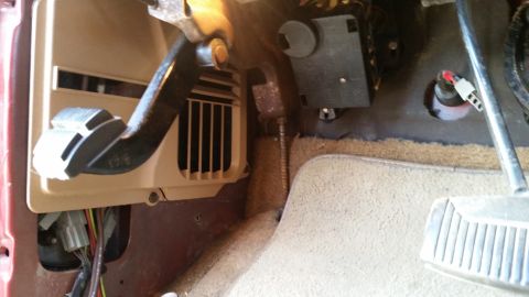 1985 Ford Bronco - The interior of a vehicle shows the brake and gas pedals, along with a vent and wiring harness under the dashboard.