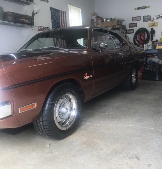 Brown 1971 Dodge Dart with black stripe and hood scoop parked in a garage.