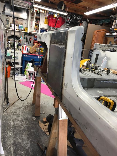 1992 Jeep Wrangler - A partially repaired vehicle body panel is supported by wooden sawhorses in a garage. The panel has a freshly welded section with visible s…