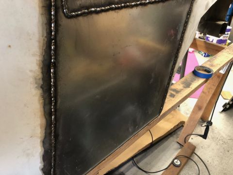 1992 Jeep Wrangler - A close-up view shows a freshly welded metal panel on a vehicle build. The panel is supported by wooden beams and a roll of blue painter's…