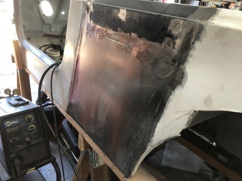 1992 Jeep Wrangler - A close-up view of a vehicle's body panel undergoing repair, showing welding marks and primer. A Miller welding machine is visible in the f…