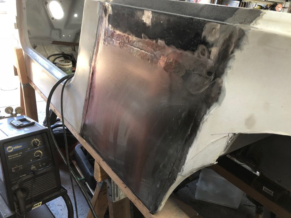 Vehicle body panel repair with welding and primer, Miller welder in foreground.