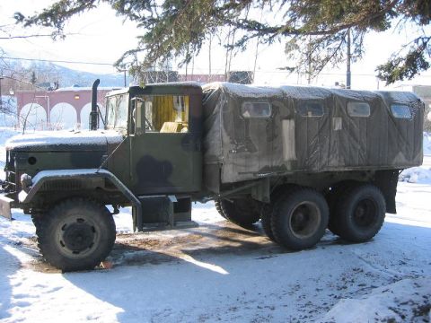 1985 Ford Bronco - A camouflaged military truck with a canvas top sits in a snowy environment.