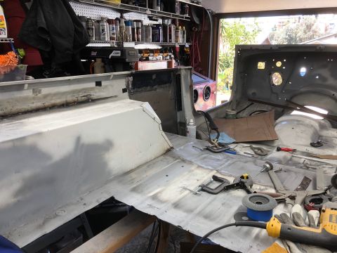 1992 Jeep Wrangler - The interior of a Jeep Wrangler is being worked on, with the floor pan and rear tub exposed. Various tools, including clamps, grinders, and…