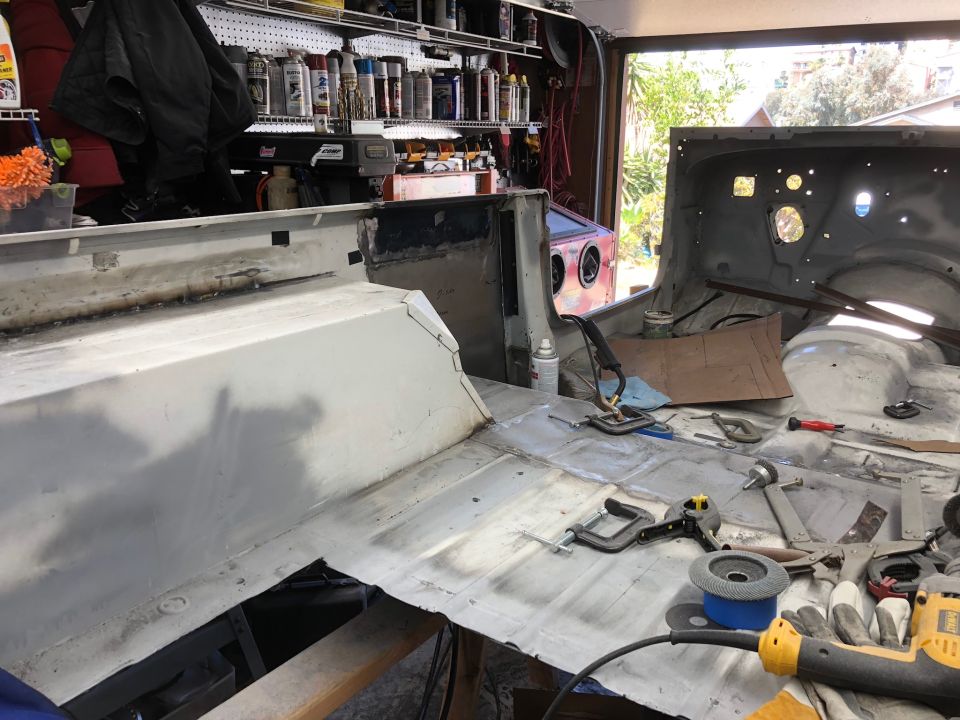 Interior of a Jeep Wrangler undergoing restoration, showing floor pan and tools.