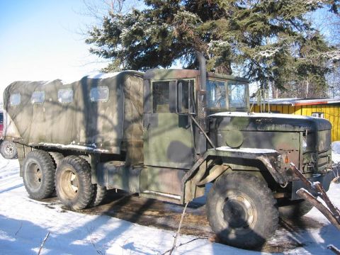1985 Ford Bronco - This heavy-duty military truck features a camouflage paint scheme and a canvas-covered cargo area, seen here in a snowy environment.