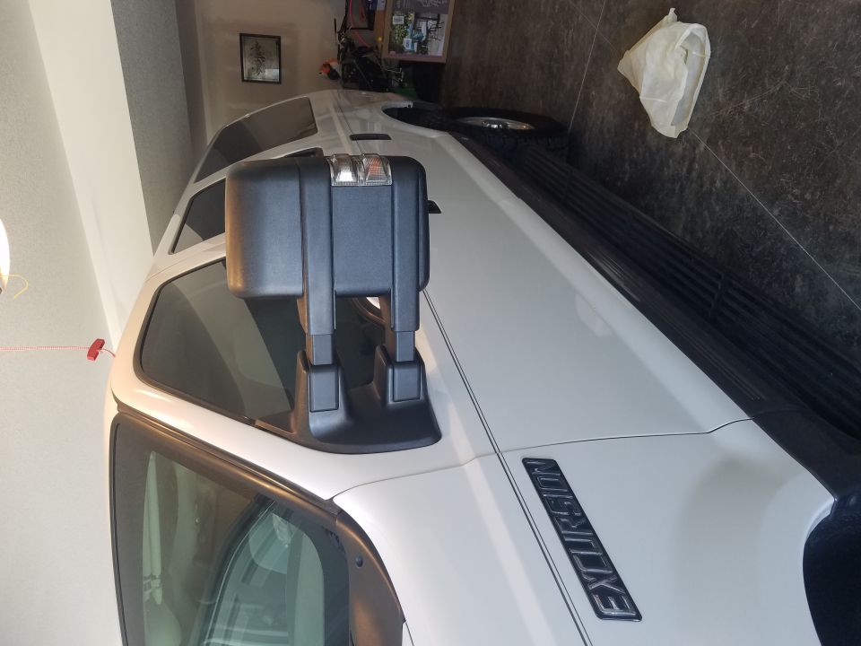 White Ford Excursion side view in a garage showing towing mirror, EXCURSION fender badge, and running board