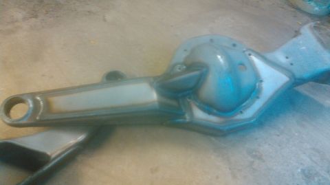 1992 Ford Bronco - Close-up of a stripped and prepped Twin Traction Beam front axle arm resting on a concrete floor, showing the cast differential housing wit…