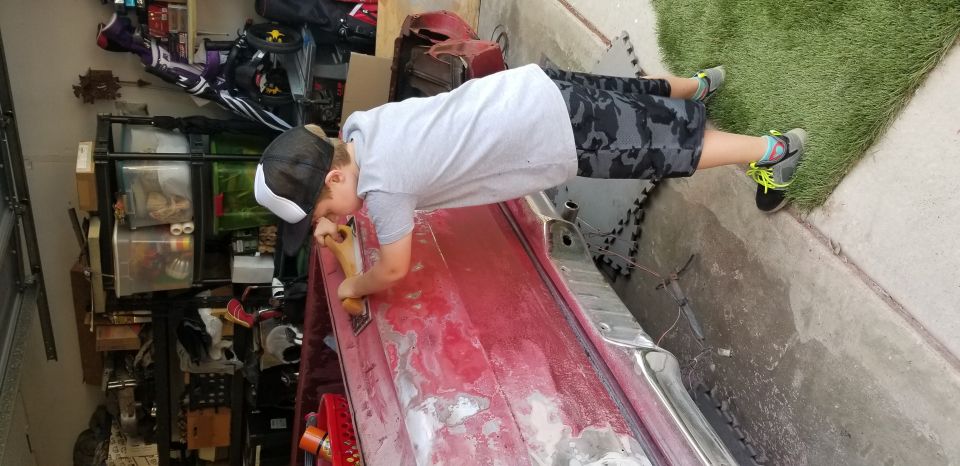 Person sanding red vehicle body