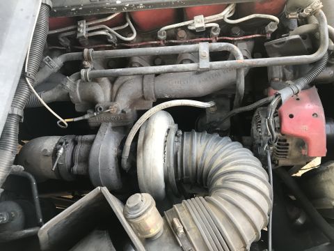 1997 Dodge 3500 - Close-up view of a diesel engine's turbocharger and exhaust manifold. The turbocharger housing is gray and dusty, with a large, ribbed inta…