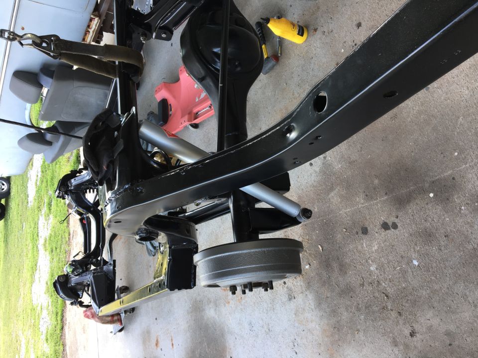 Black painted vehicle frame with suspension, differential, and brake drum.