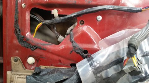 1985 Ford Bronco - This is a close-up view of the interior door panel of a red vehicle, showing wiring and insulation. The image focuses on the internal compo…