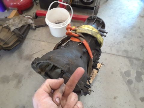 1996 Ford F-350 - Transmission assembly on a pallet, with a hand in the foreground. Other parts are in the background.