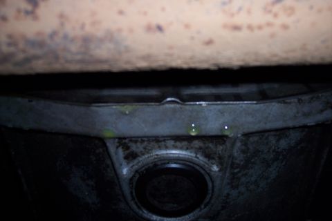1995 Ford Bronco - Green coolant is dripping from a metal bracket on the underside of a vehicle.