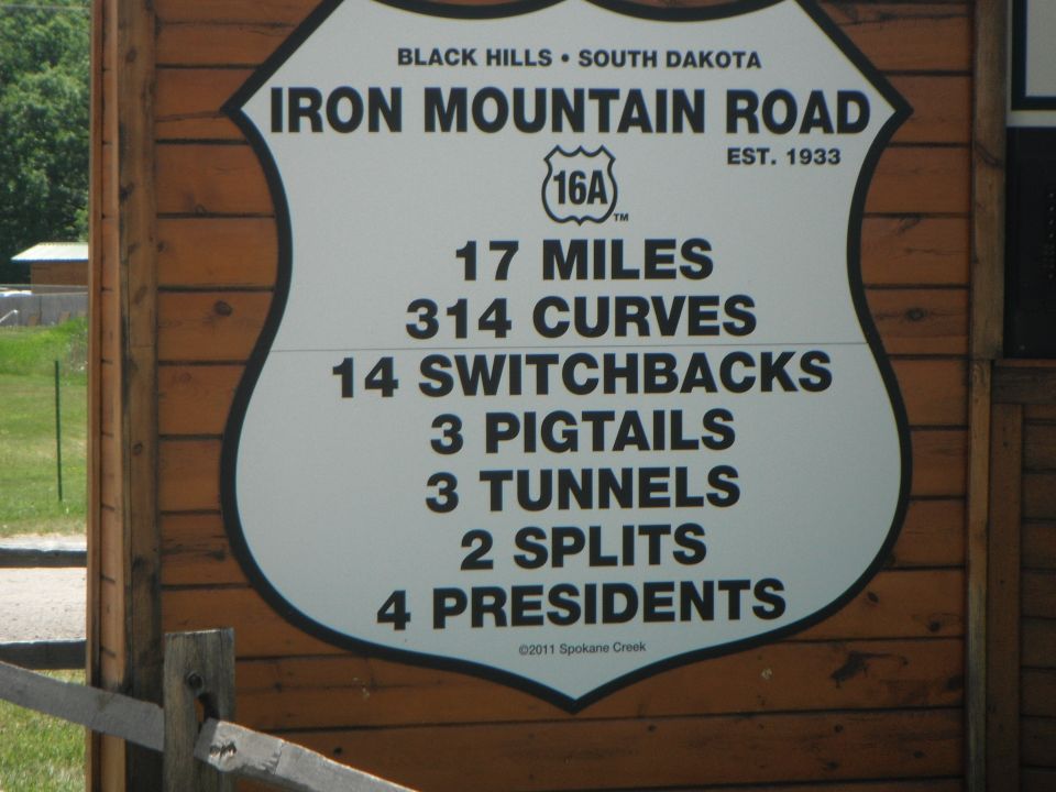 Iron Mountain Road sign in the Black Hills, South Dakota listing route stats like 17 miles and 314 curves