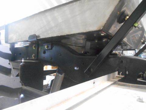 1992 Ford Bronco - A close-up view of the underside of a vehicle, showing a large metal tank mounted to the chassis with black brackets and bolts. Visible com…