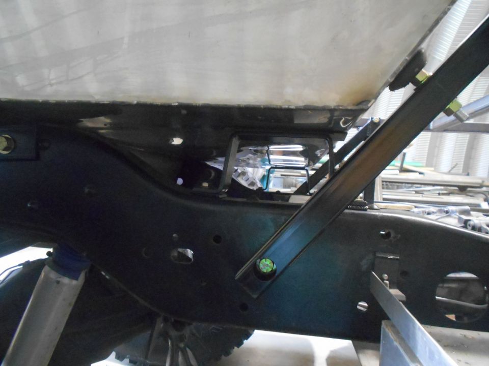 Underside of vehicle frame with metal tank and shock absorber.