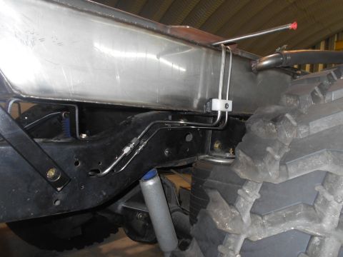 1992 Ford Bronco - A close-up view of the undercarriage of a custom vehicle, showing a large metal fuel tank mounted above the frame, with various metal fuel…