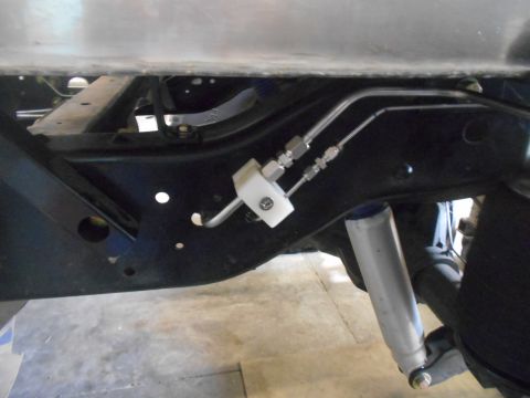 1992 Ford Bronco - A close-up view of the undercarriage of a vehicle, showing brake lines and a shock absorber attached to the frame.