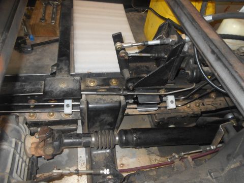 1992 Ford Bronco - This is a close-up view of the undercarriage of a vehicle, showing mechanical components like a driveshaft, cables, and hydraulic lines att…