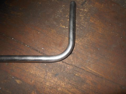 1992 Ford Bronco - A bent metal rod lies on a wooden surface. The rod is silver and has a rounded bend in the middle. The wooden surface is dark brown and app…