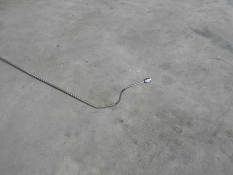 1992 Ford Bronco - A bent metal tube with a fitting on the end lies on a concrete surface.