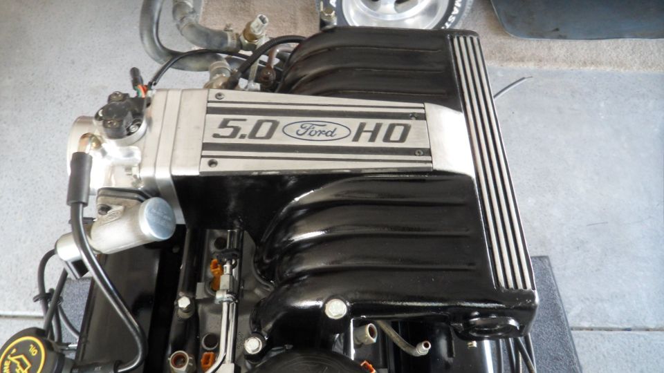 Overhead view of a Ford 5.0 HO engine with black intake manifold and silver badging.