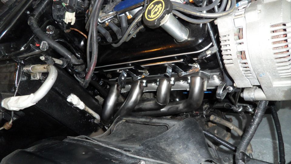 Close-up of V8 engine exhaust headers and alternator.