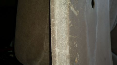 1985 Ford Bronco - Close-up view of the textured interior trim panel of a vehicle, showing a seam and some dirt or wear marks. The panel is a neutral, muted c…