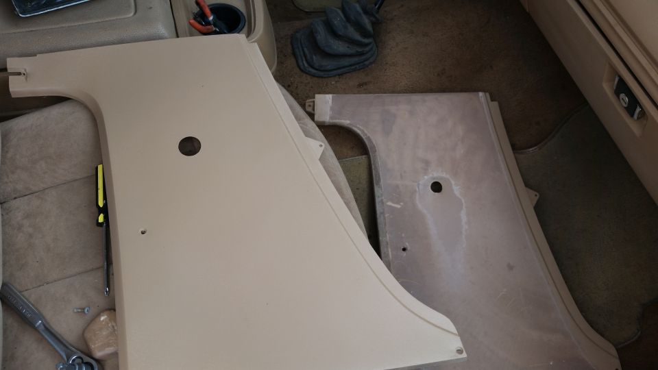 Two tan interior door panels on a vehicle floor, one new, one worn.