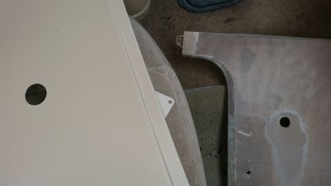 1985 Ford Bronco - A close-up view shows a beige panel with a circular cutout on the left, and a metal panel with a similar cutout on the right. A small trian…