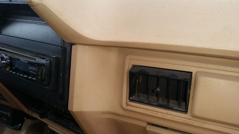 1985 Ford Bronco - The image shows a close-up view of the interior dashboard of a vehicle, focusing on a car stereo and an air vent.