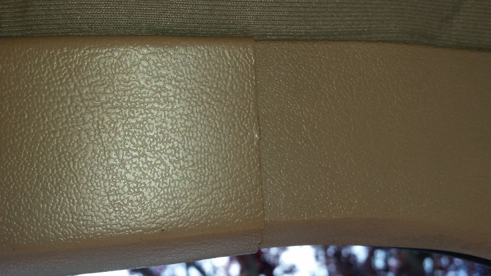 Close-up of textured beige interior trim with a seam, and dark fabric above.