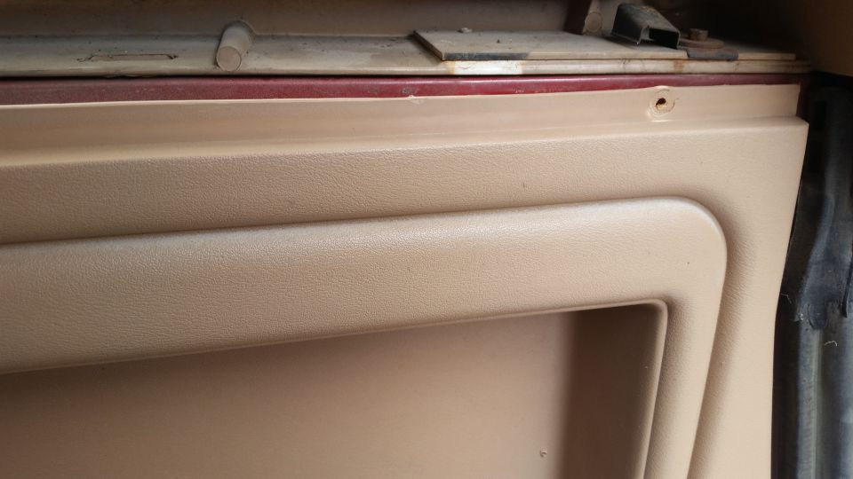 Tan interior door panel with a screw hole.