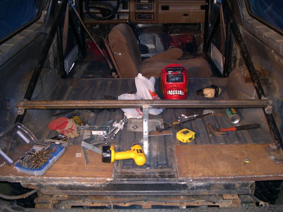 Vehicle interior with roll cage, tools, and a red welding mask