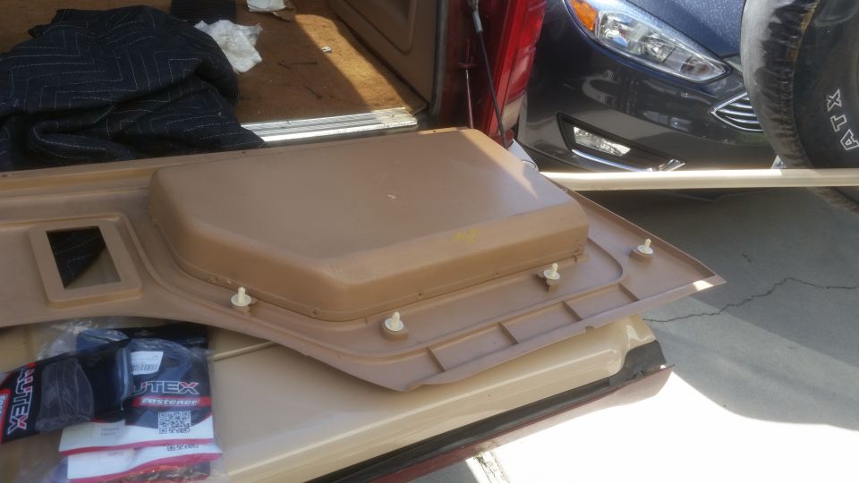 Tan interior door panel with white fasteners and a package of fasteners.