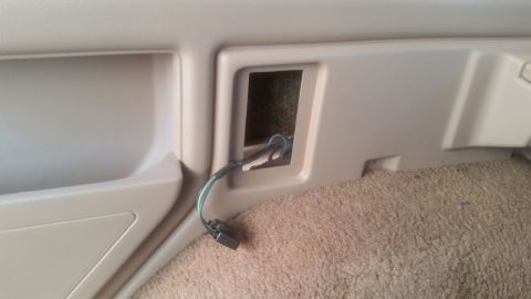 1985 Ford Bronco - A close-up view of a tan interior panel in a vehicle, showing a rectangular cutout with a wire harness emerging from it. The wire harness h…
