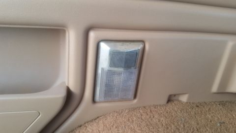 1985 Ford Bronco - A close-up interior shot shows a tan plastic panel with a light fixture. The fixture has a clear, textured lens and a gray directional cove…