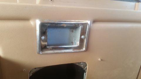 1985 Ford Bronco - A close-up view of a tan interior panel with a chrome-trimmed rectangular opening. The opening appears to be for a radio or gauge, with vis…