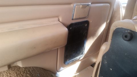 1985 Ford Bronco - Interior shot of a tan vehicle's door panel and seat. Visible are a vent, a handle, and part of a seat cushion.