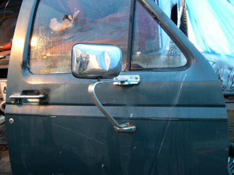 1986 Ford Bronco - Close-up of a vehicle door and its side mirror, showing part of the window frame.