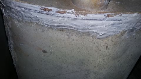 2000 Pontiac Grand Prix - A close-up view shows a thick layer of gray sealant applied to the top edge of a rough, textured concrete or stone structure. The sealant i…